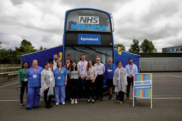 The NHS MELISSA bus team in front of the blue MELISSA bus.