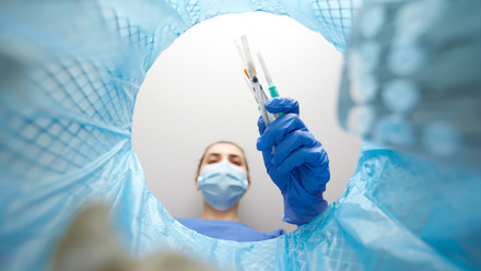 Healthcare worker in gloves throwing used needles in the bin.